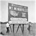 2 men standing by large Welcome to McMinnville sign.