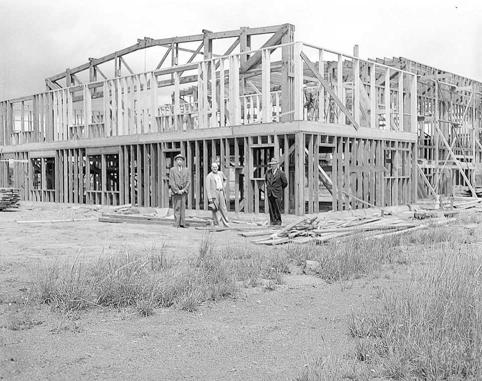 3 men standing in front of building being constructed.