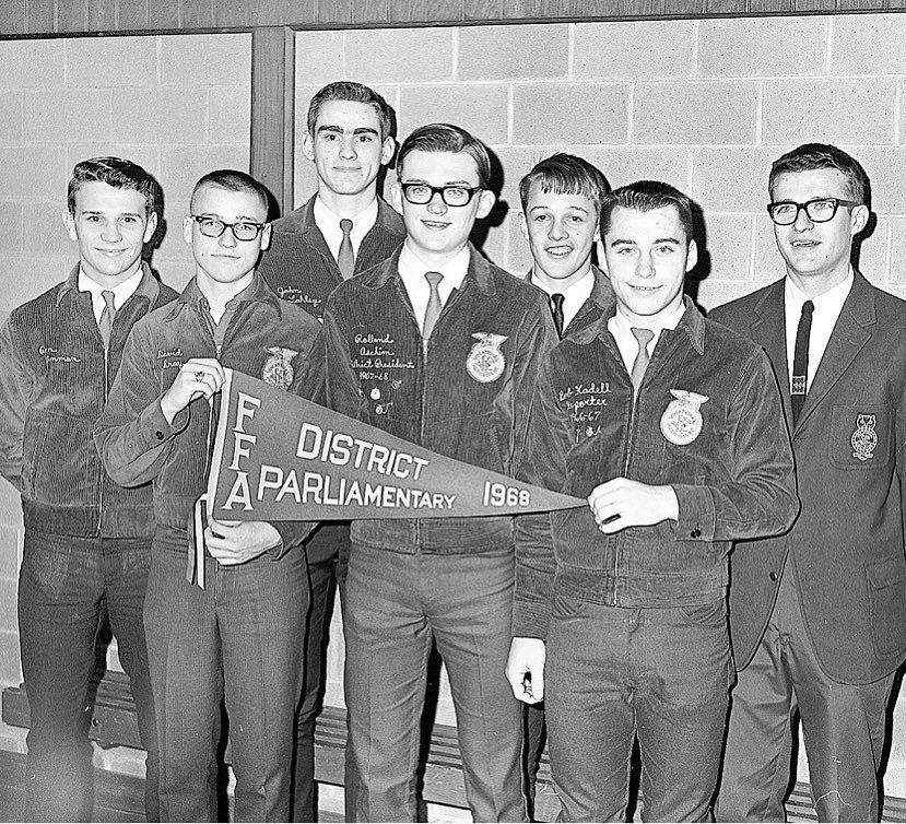 Boys standing against wall holding FFA District Parliamentary 1968 flag.