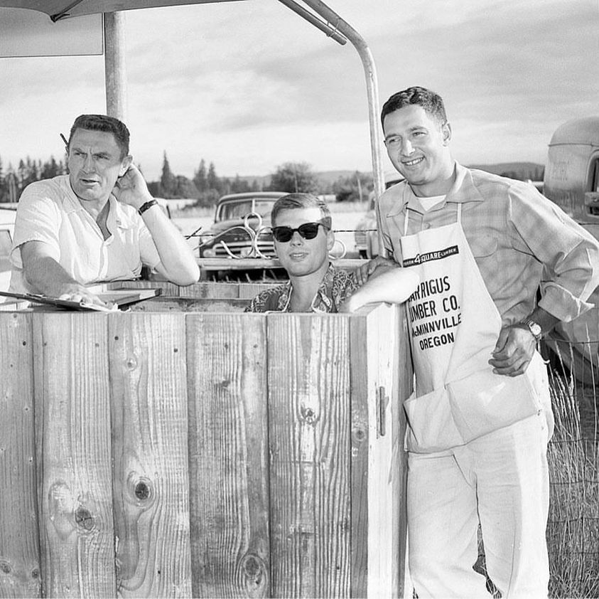 3 men at wooden booth.