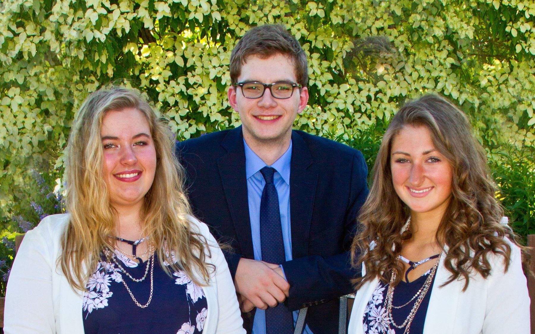 Young women and young man dressed up and smiling