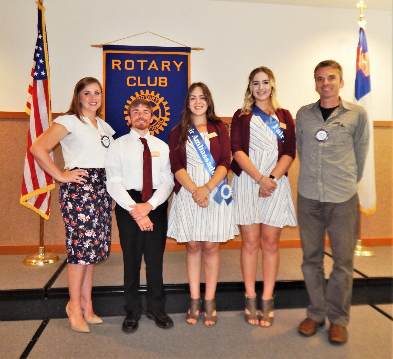 Fair Ambassadors standing in front of Rotary Club banner