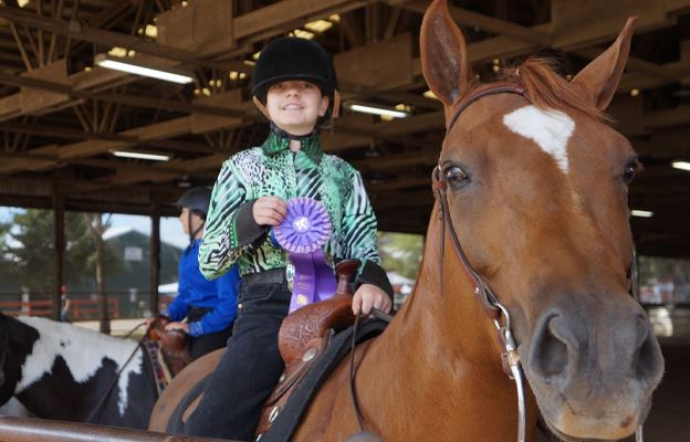 Little girl riding brown horse
